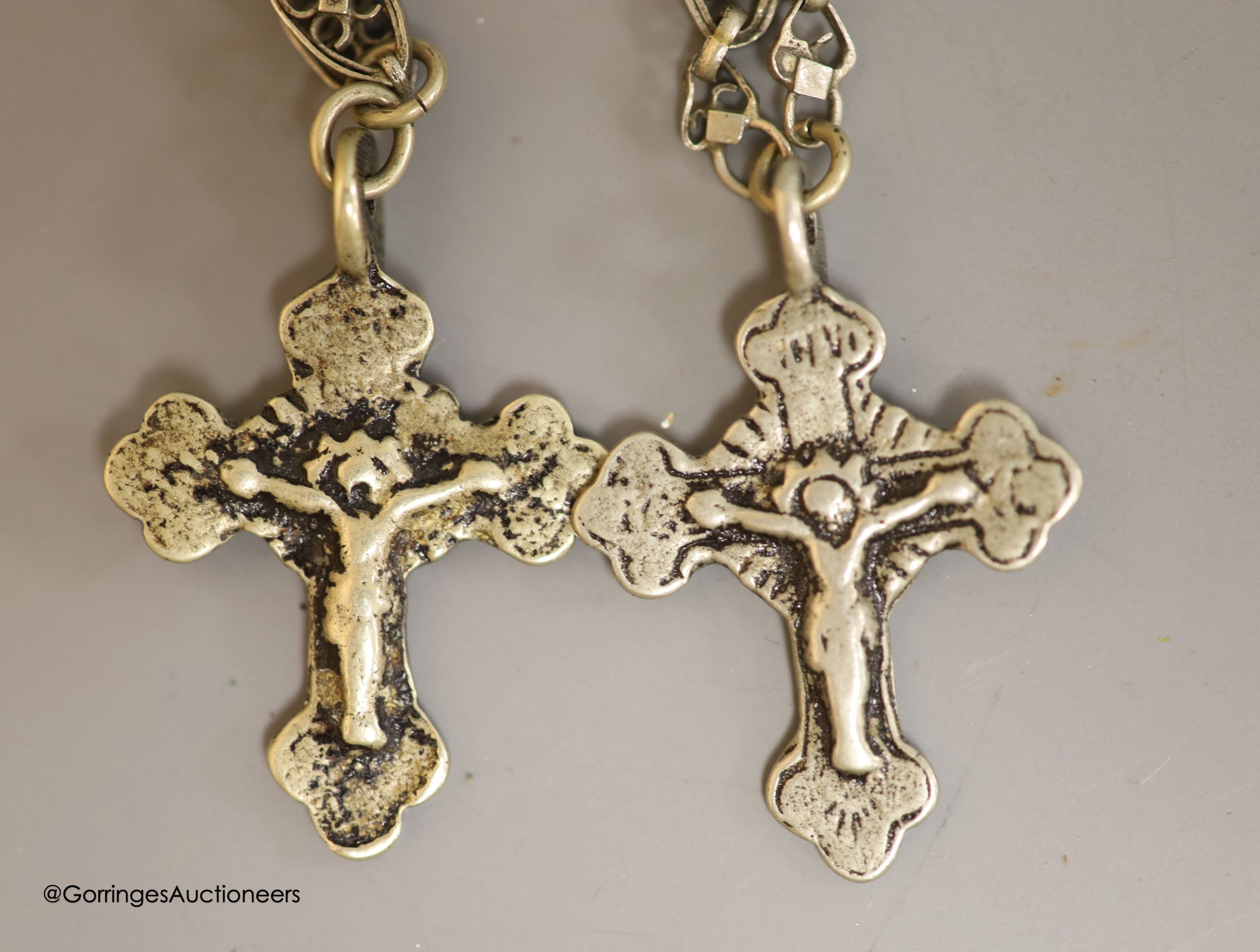 Two Russian white metal crucifixes on pierced oval link neck chains and a cast brass scribes ink pot.